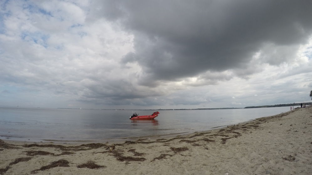 Ein rotes Schaluchboot in der weiten Bucht vor Bülk